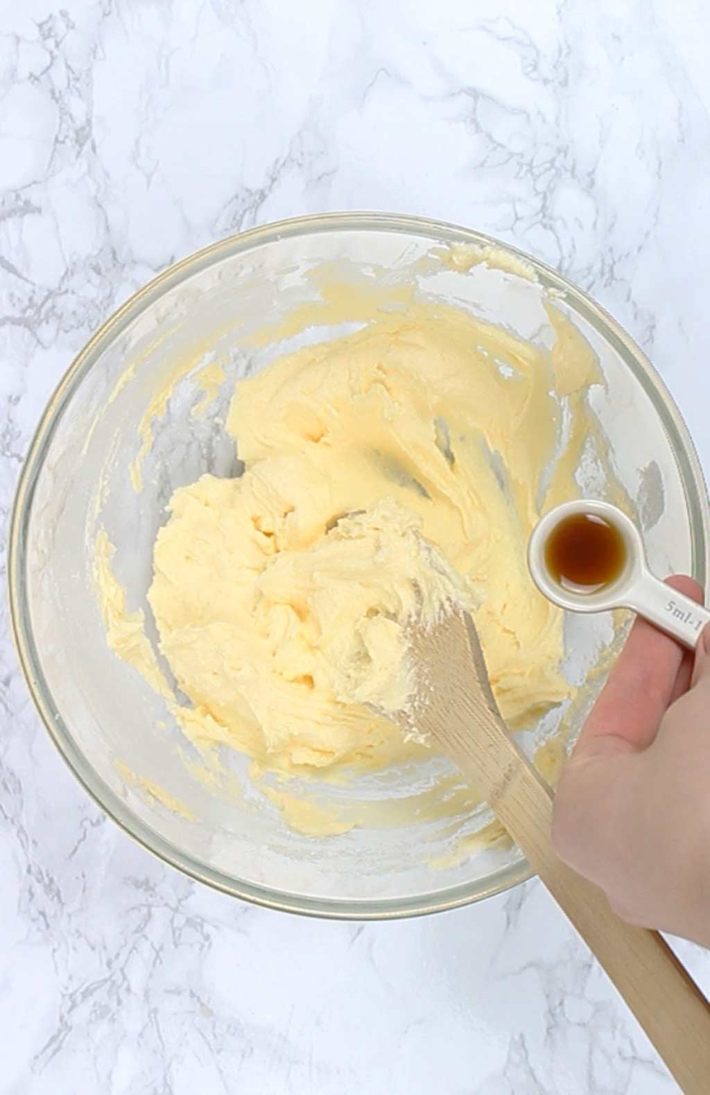 pouring vanilla into butter and sugar mix