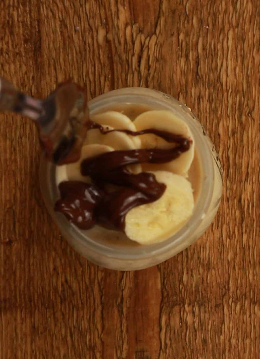 Drizzling Chocolate Spread Over The Bananas On Top Of The Oats