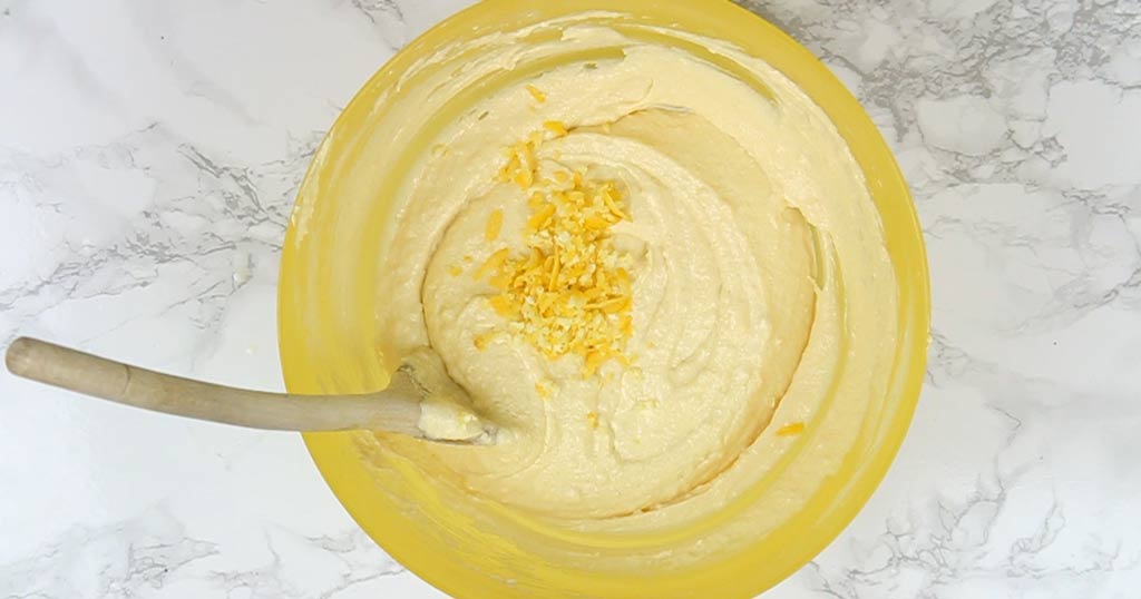 lemon zest in bowl with cake batter waiting to be mixed