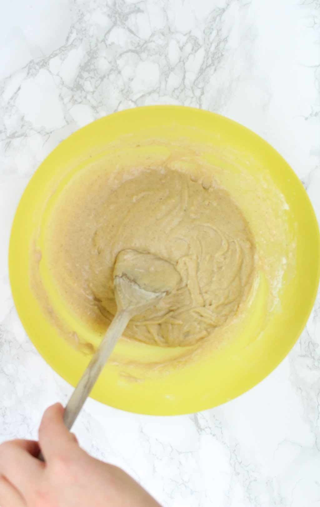 Hand mixing donut batter in a bowl