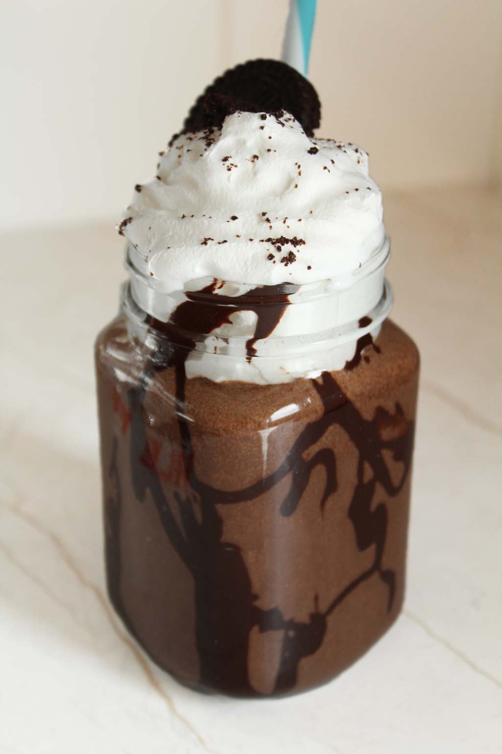 Cookies and cream milkshake in a glass jar topped with whipped cream and an Oreo 