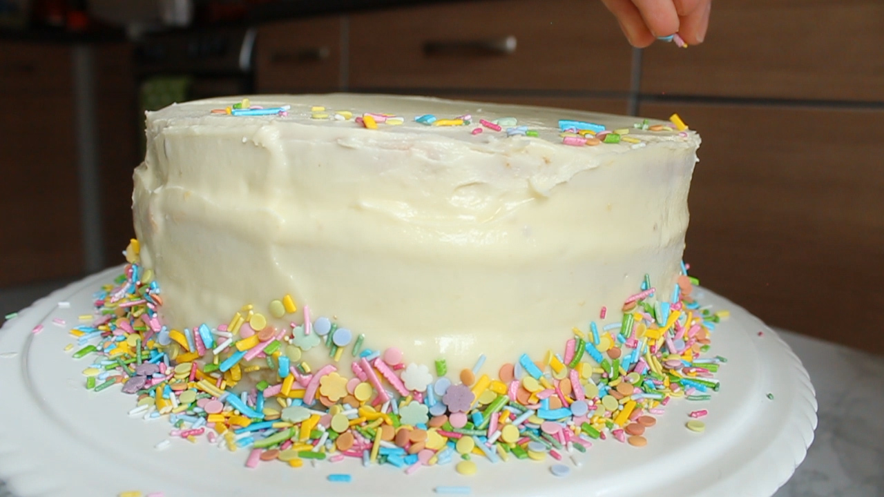 adding sprinkles onto the top of the cake