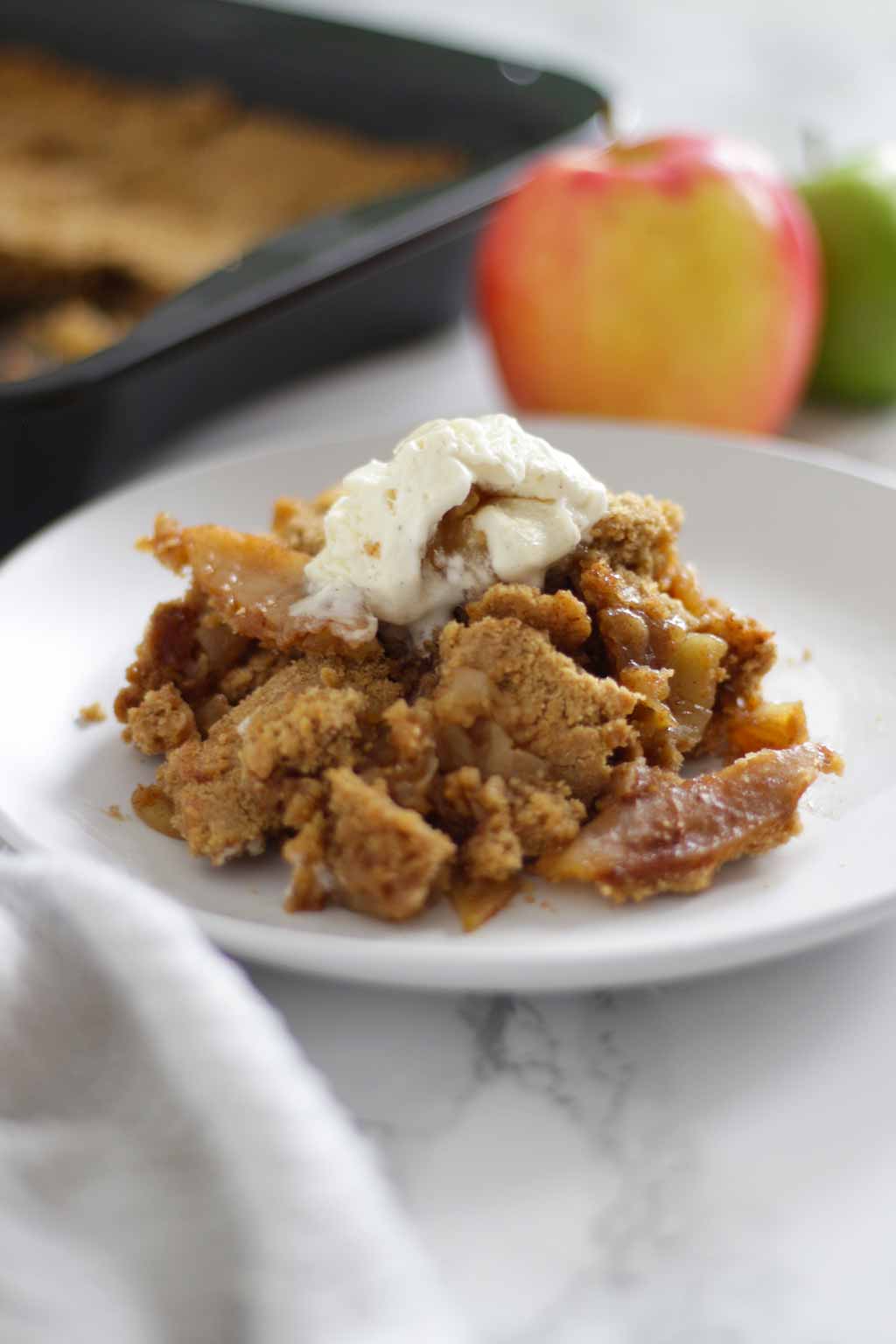 Vegan Apple Crumble on a plate with ice cream on top