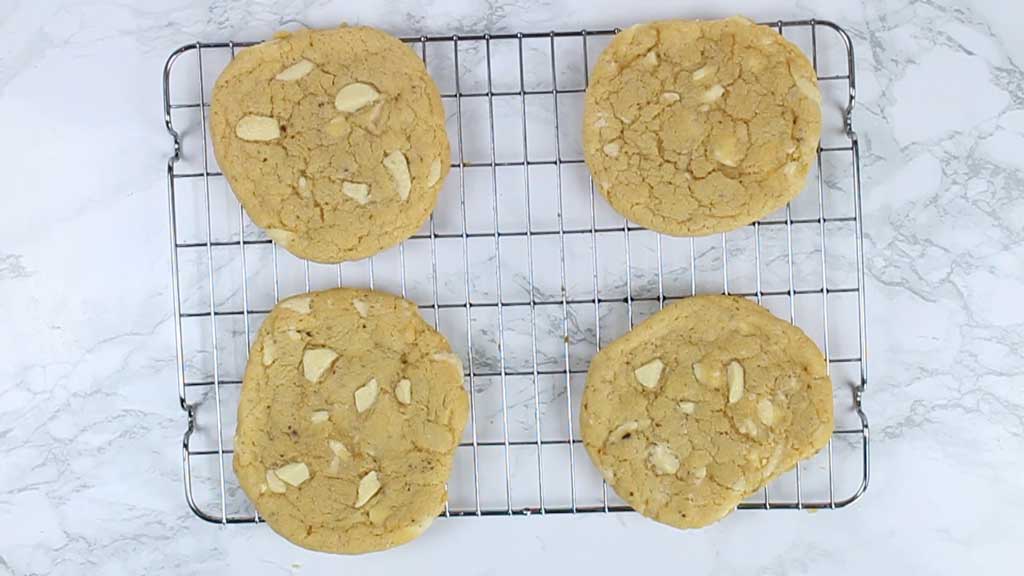 4 white chocolate chip cookies on a cooling rack