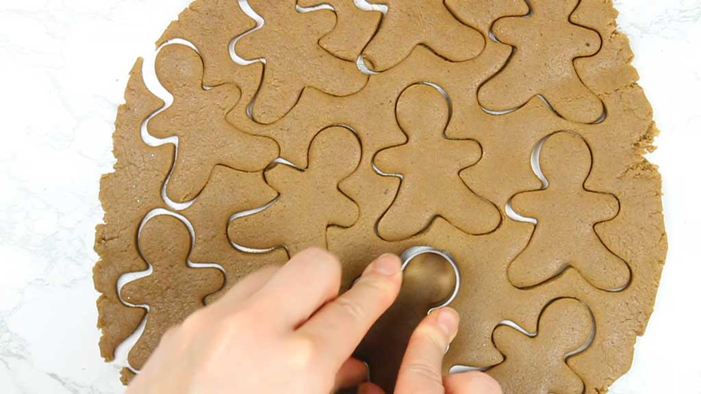 cutting gingerbread man shapes out of the rolled out dough