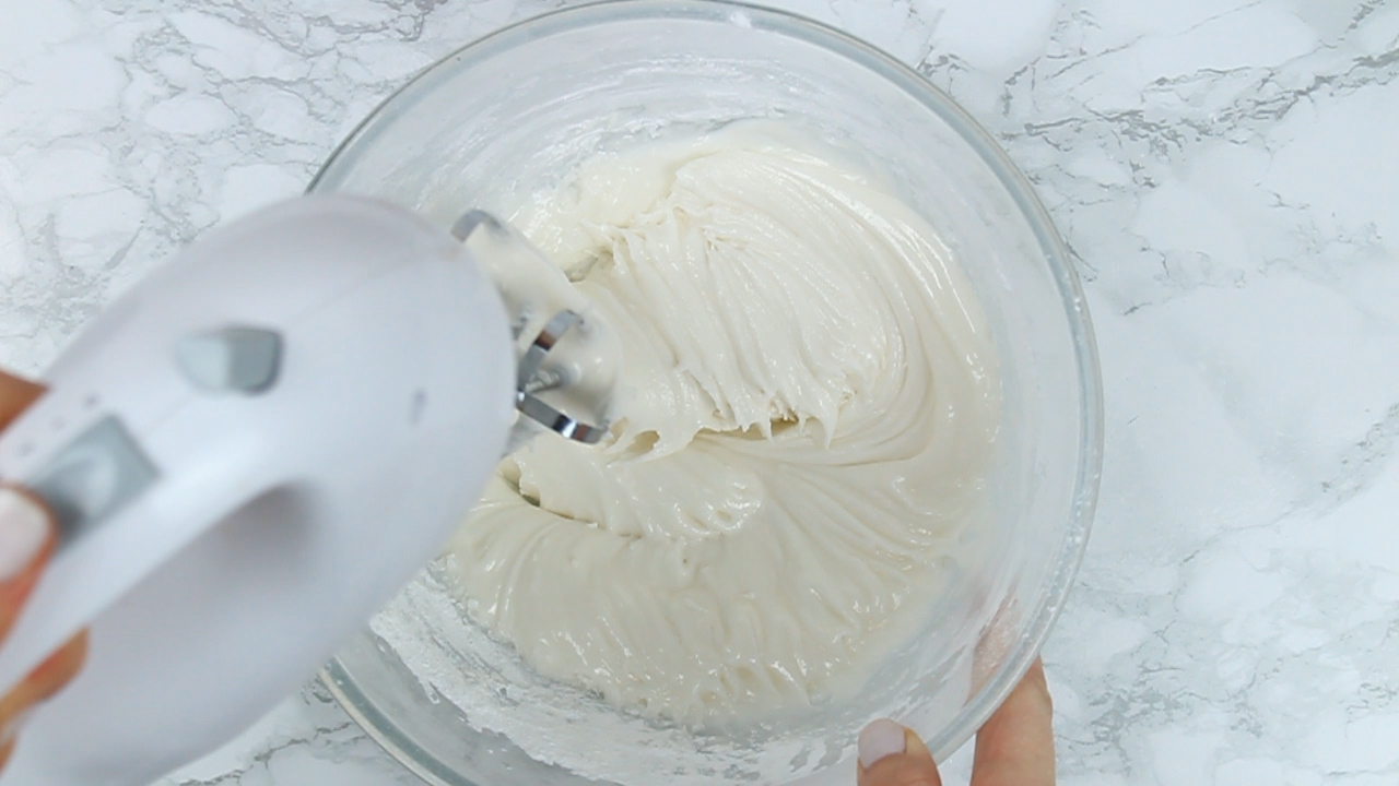 whisking the royal icing with an electric hand whisk