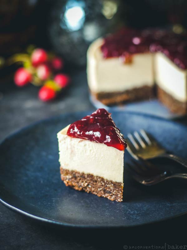 a slice of cherry cheesecake on a black plate with a fork