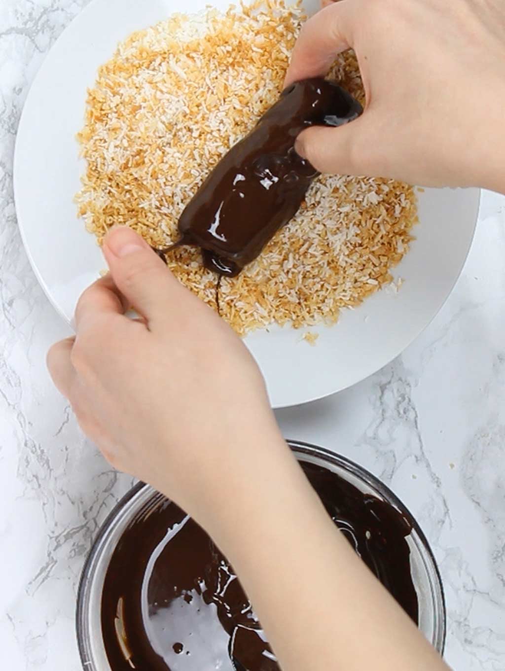 rolling the chocolate-dipped bars in the desiccated coconut mix