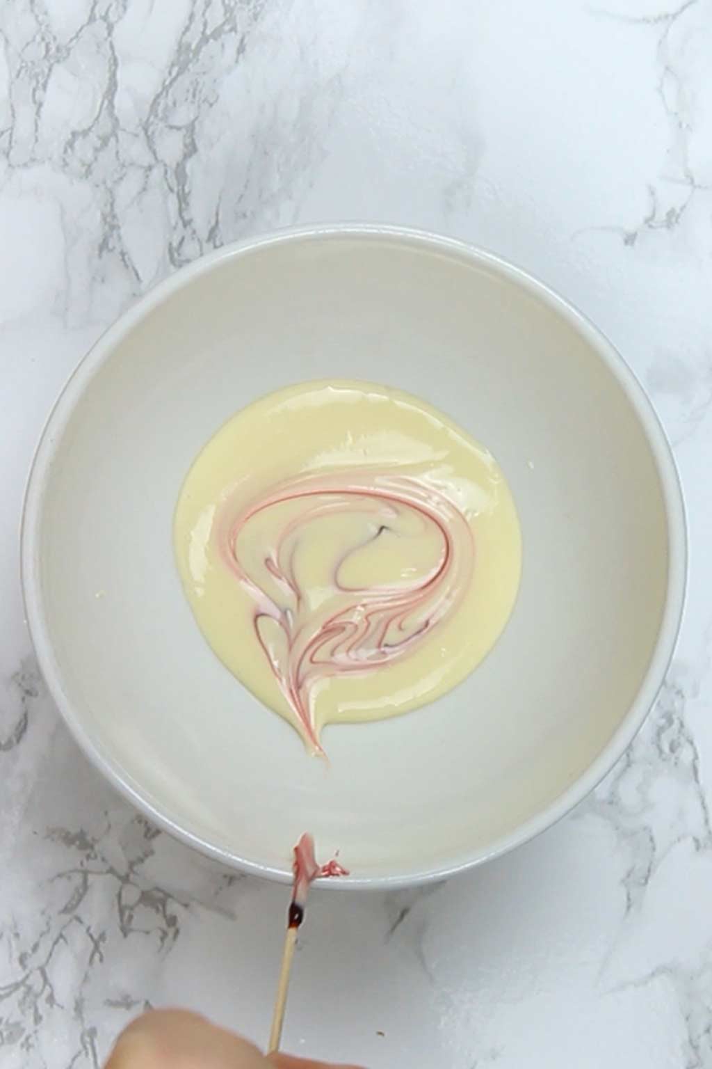 adding pink food gel to white chocolate using a toothpick