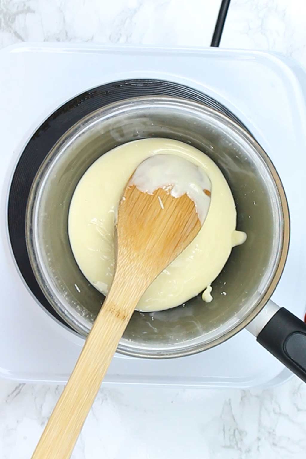 melted white chocolate in a pot with a wooden spoon in