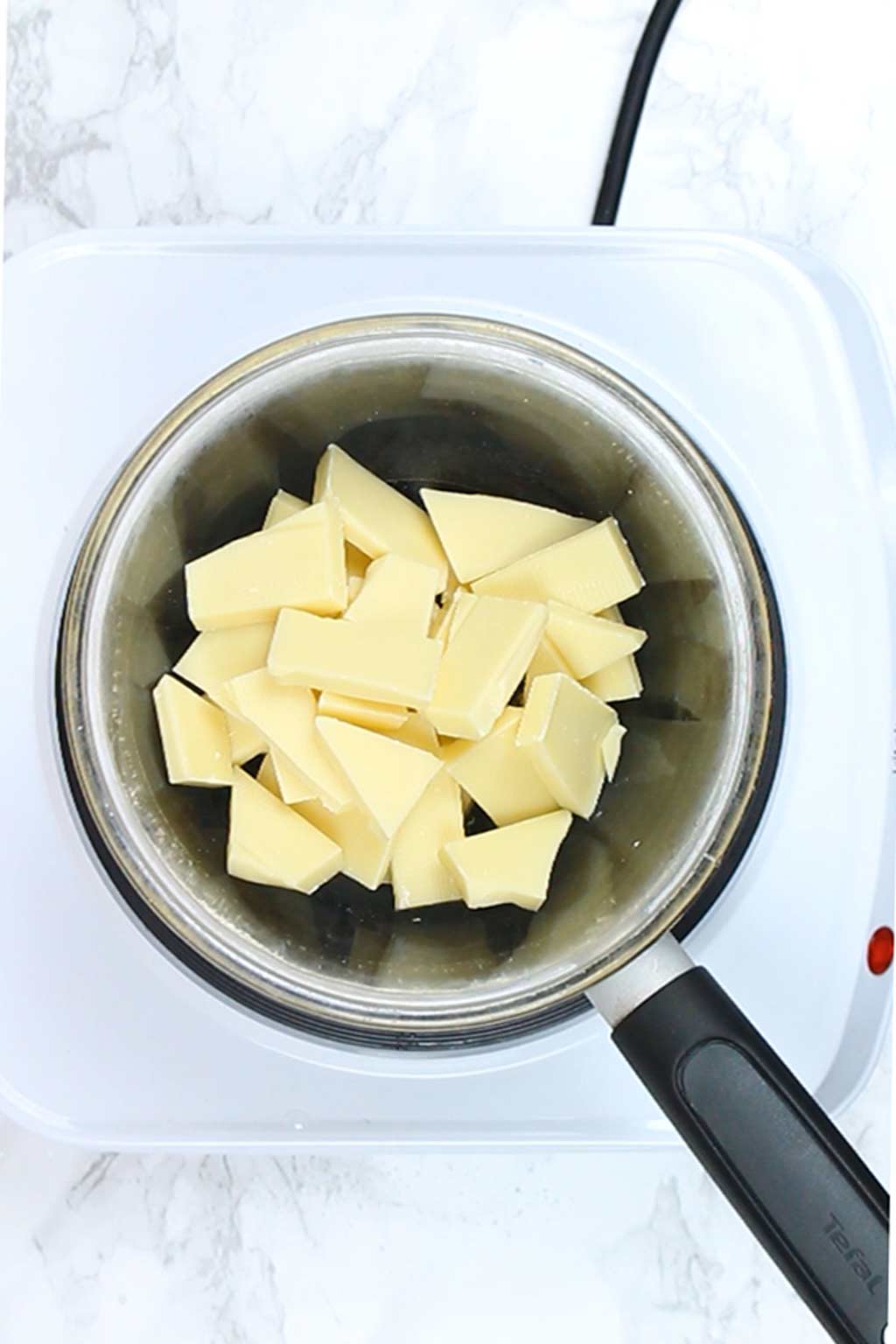 chopped white chocolate in a bowl over a pot of simmering water