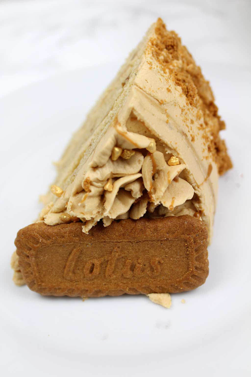 a slice of cake on a plate with a Biscoff cookie on top