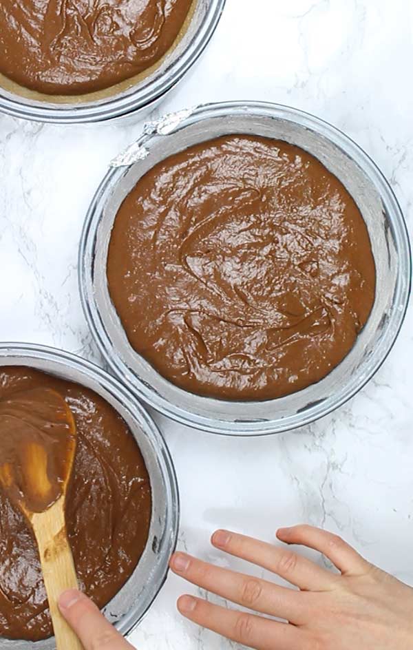 3 cake tins filled with chocolate cake batter