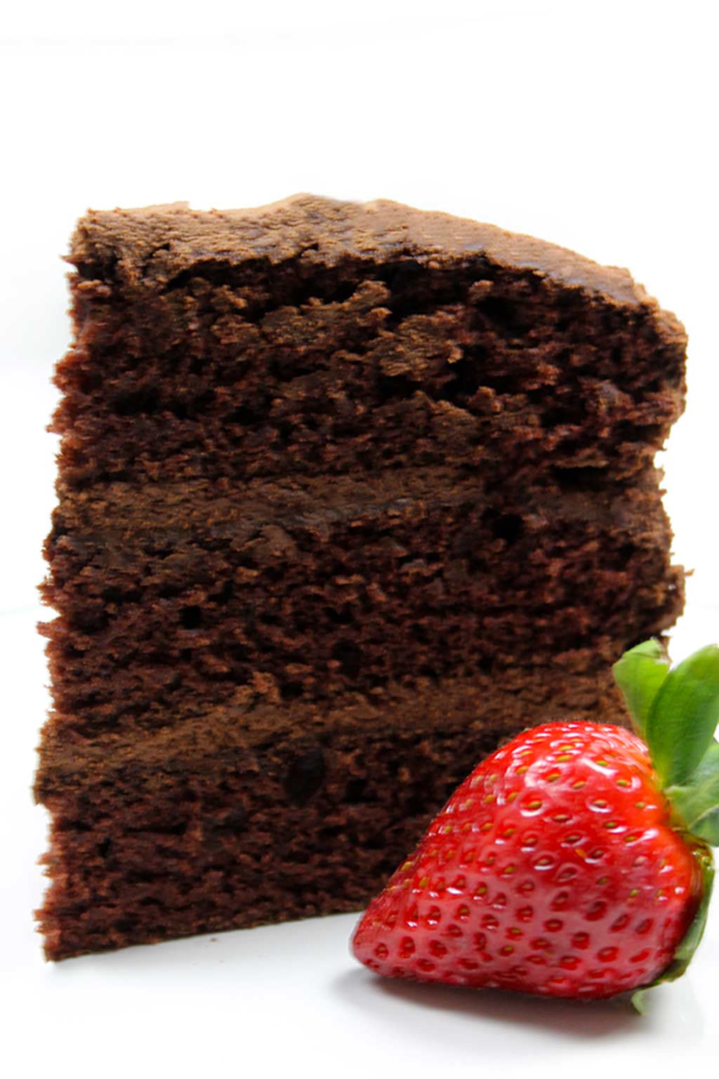 a slice of chocolate cake with a strawberry beside it
