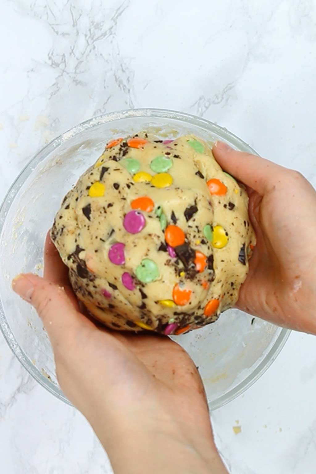 a ball of cookie dough with rainbow and chocolate chips in it