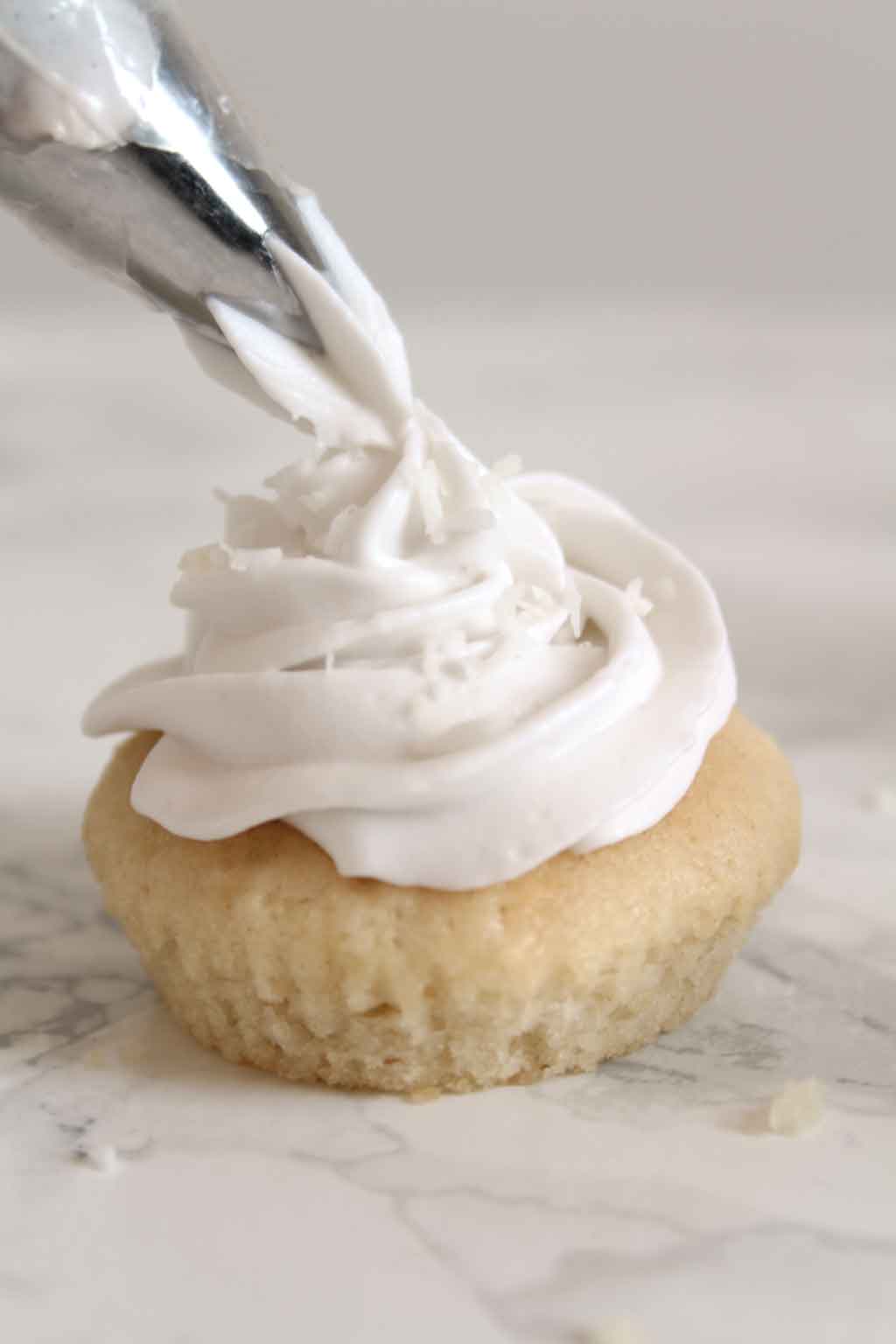 Piping vegan whipped Cream Onto A Cupcake