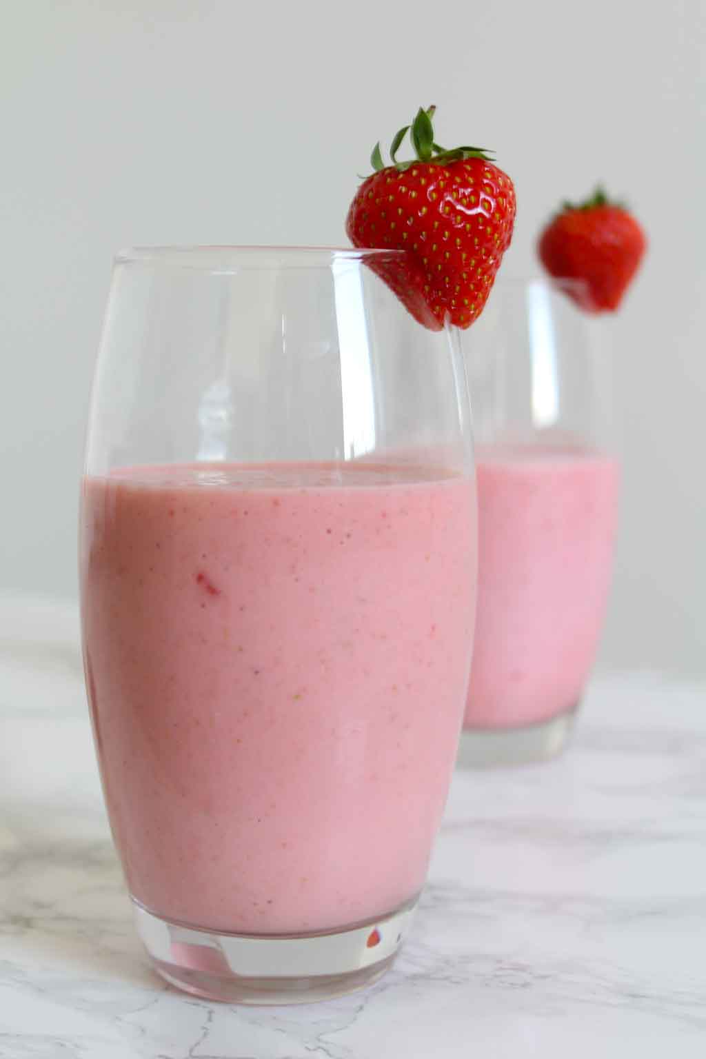 Two vegan strawberry milkshakes in glasses