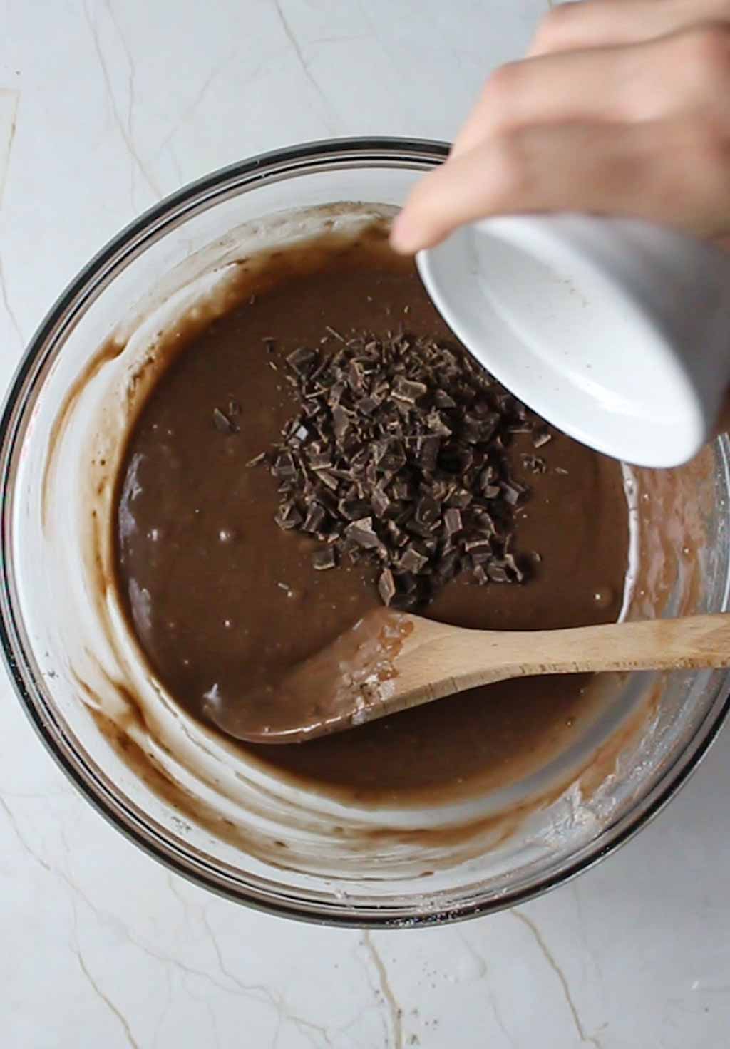 pouring chocolate chunks into the bowl of cake batter