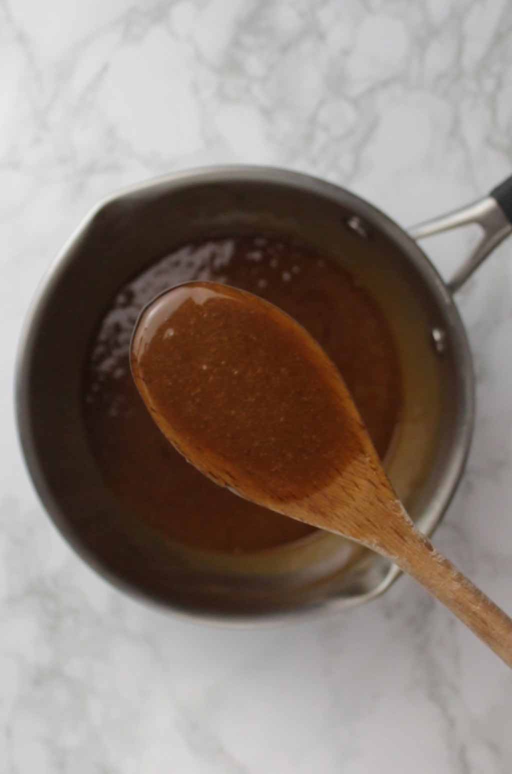 a wooden spoon sitting over a pot of Biscoff Caramel