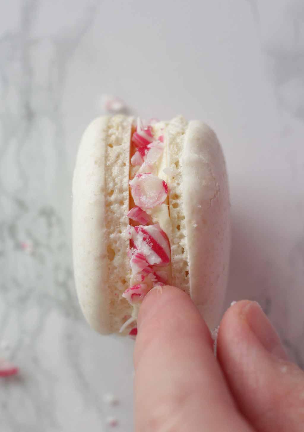 Pressing Candy Cane Pieces Into The peppermint Macaron Edges