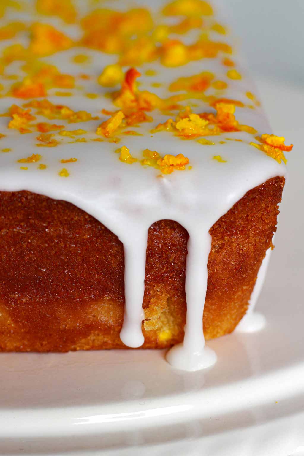 close up of Vegan Orange Cake with white icing dripping down the side