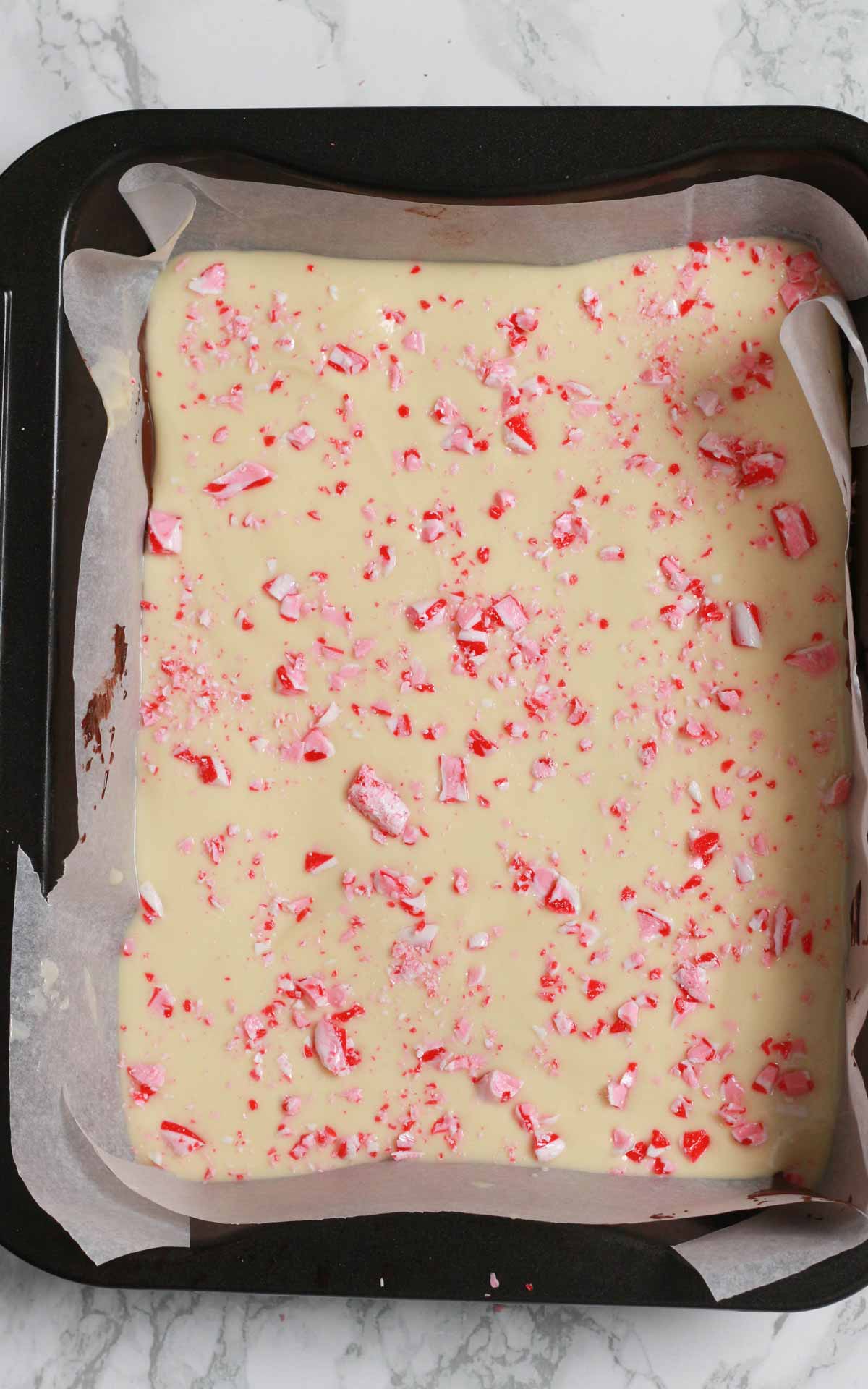 Melted dairy-free White Chocolate In Tin With Candy Cane Pieces On Top