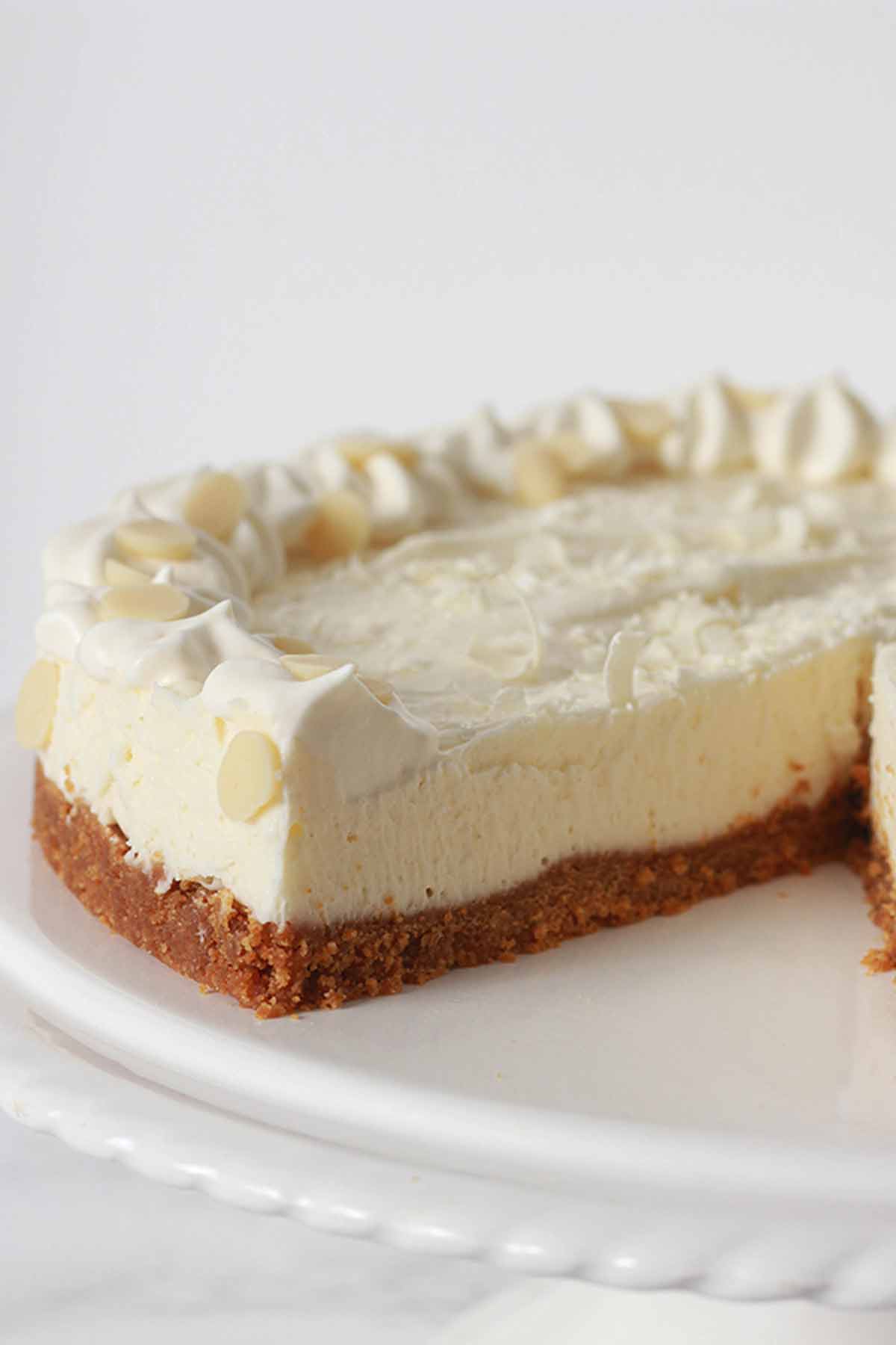 Vegan White Chocolate Cheesecake On A Stand With A Slice Taken Out