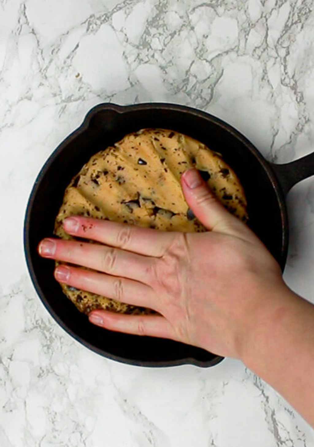 Pressing Cookie Dough Ball Into A Cast Iron Skillet