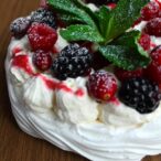 vegan pavlova with berries, whipped cream and a sprig of mint on top