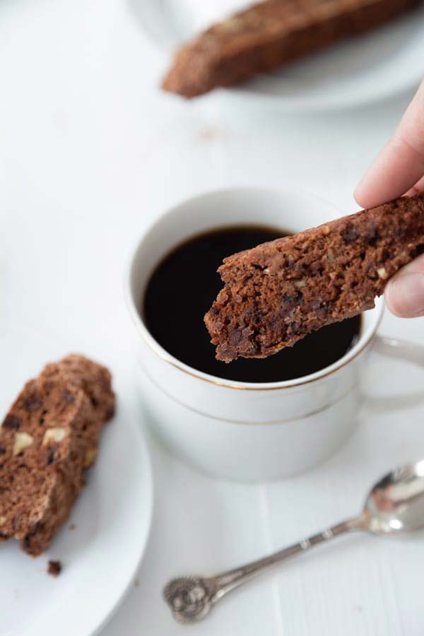 piece of biscotti being dipped into chocolate sauce