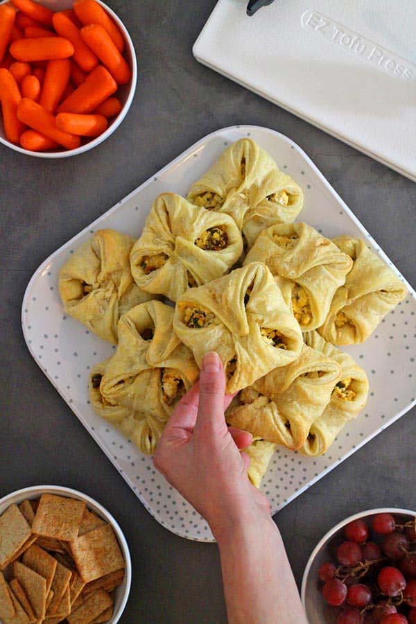 Hand grabbing a ricotta puff from plate