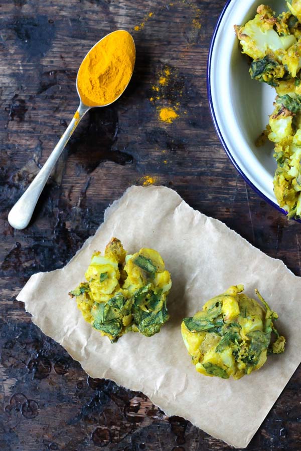 Two pakoras on counter beside a spoonful of spice