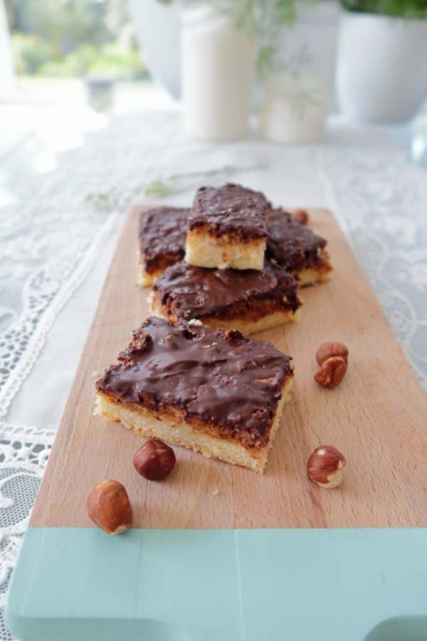 Slices of chocolate hazelnut bars on a board with hazelnuts scattered around