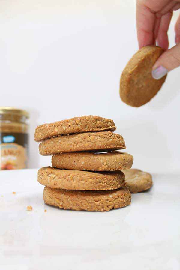 Hand lifting a peanut butter cookie from a stack