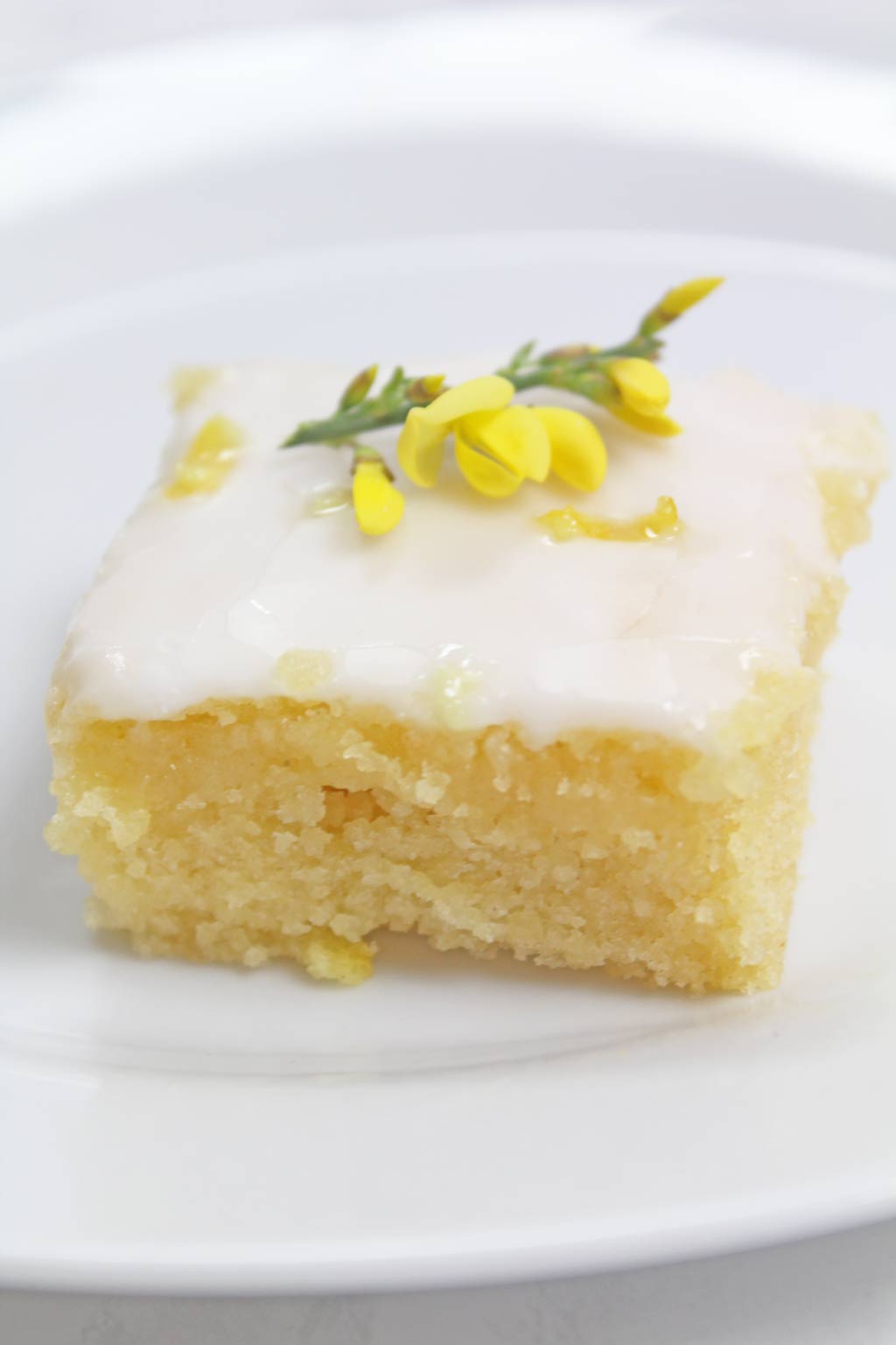 slice of vegan lemon drizzle cake with yellow flower on top