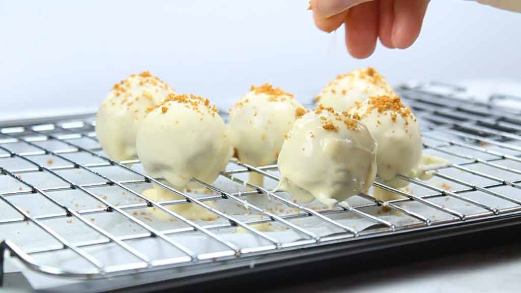 sprinkling cookie crumbs on top of the cheesecake bites