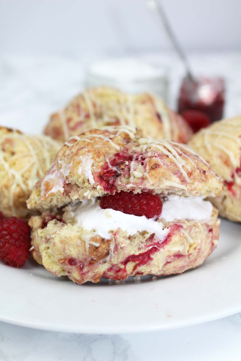 Vegan raspberry white chocolate scone on a plate with whipped cream in the middle