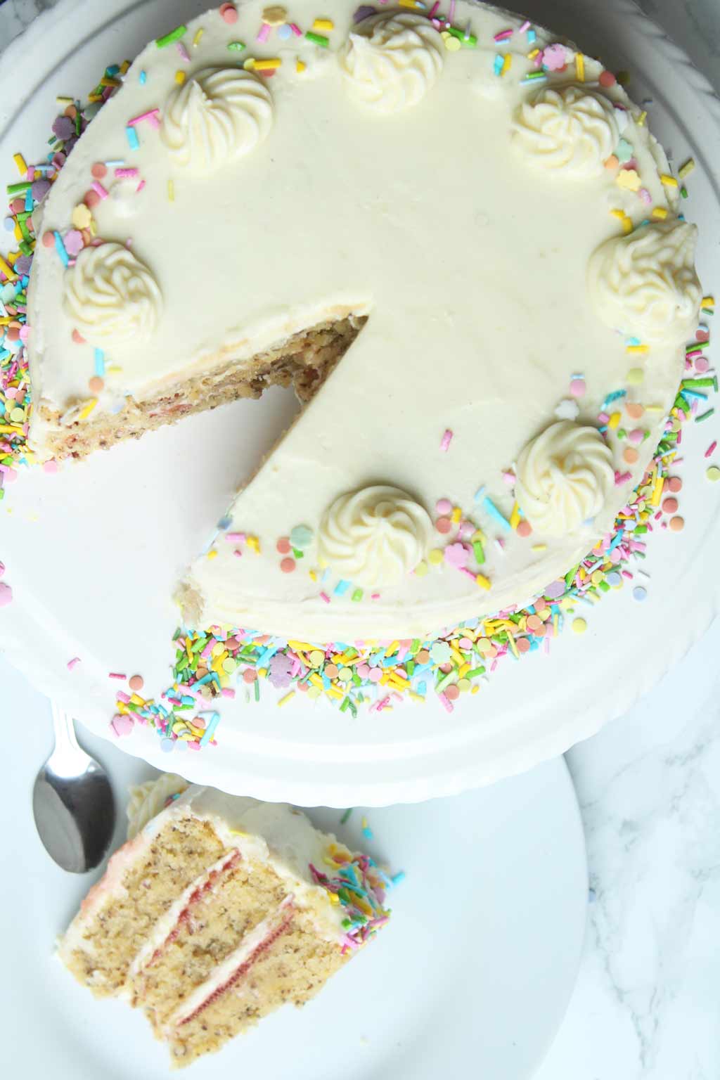 vegan birthday cake on a stand with one slice beside it on a plate