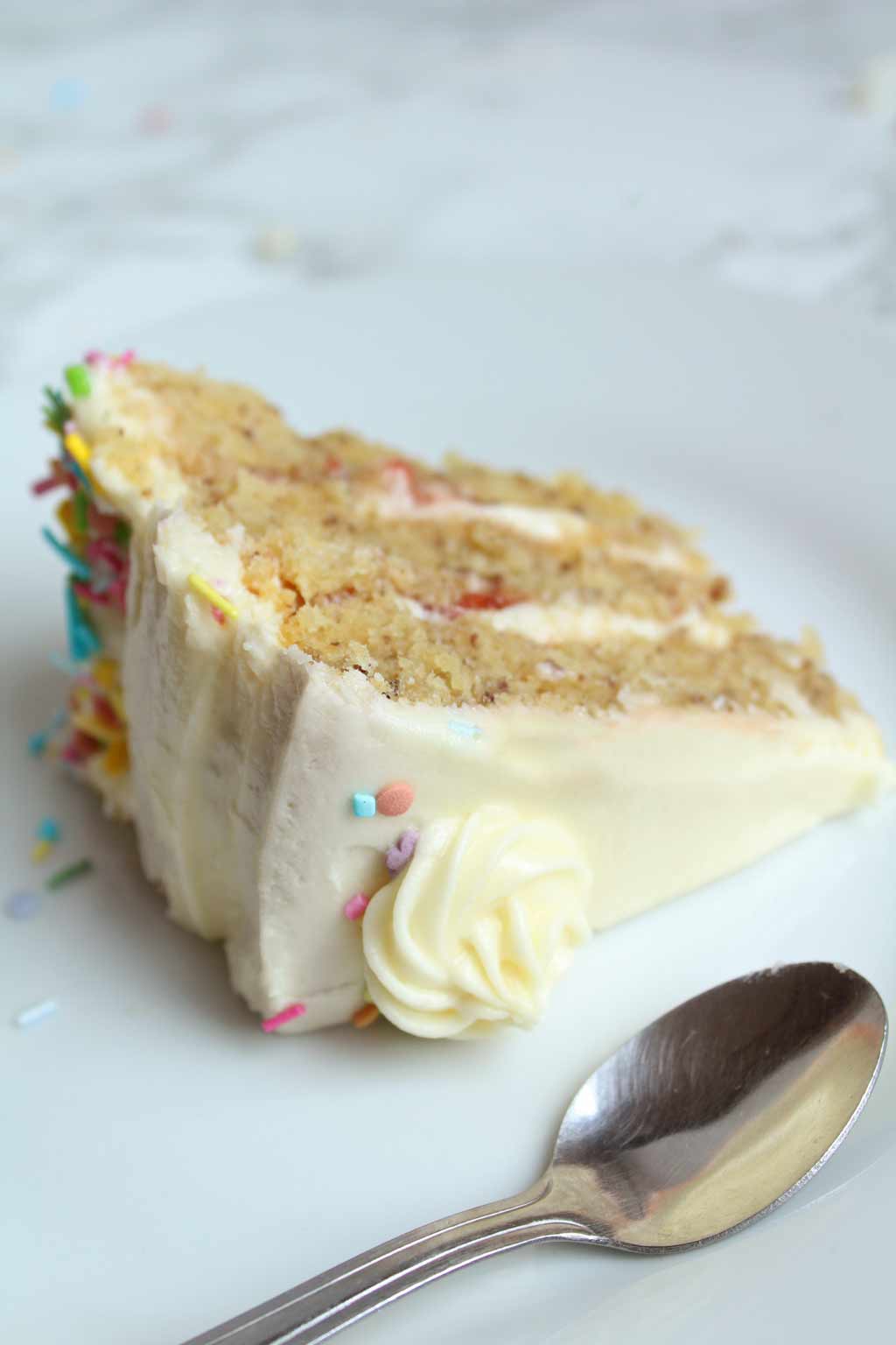 a slice of vegan birthday cake and a spoon on a small plate