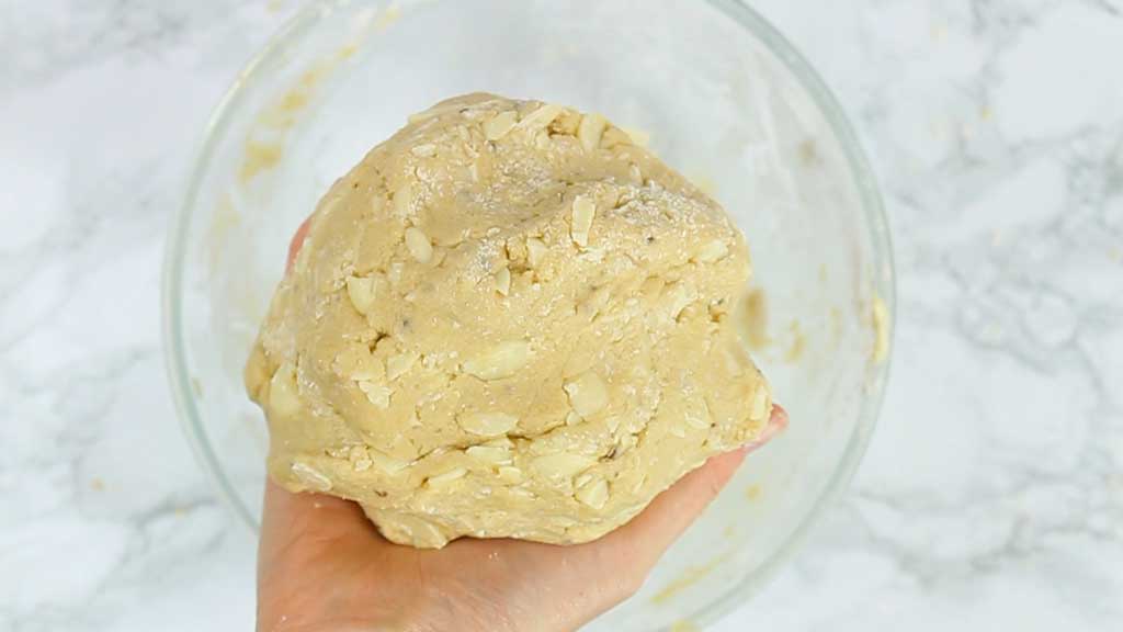 hand holding a ball of white chocolate chip cookie dough