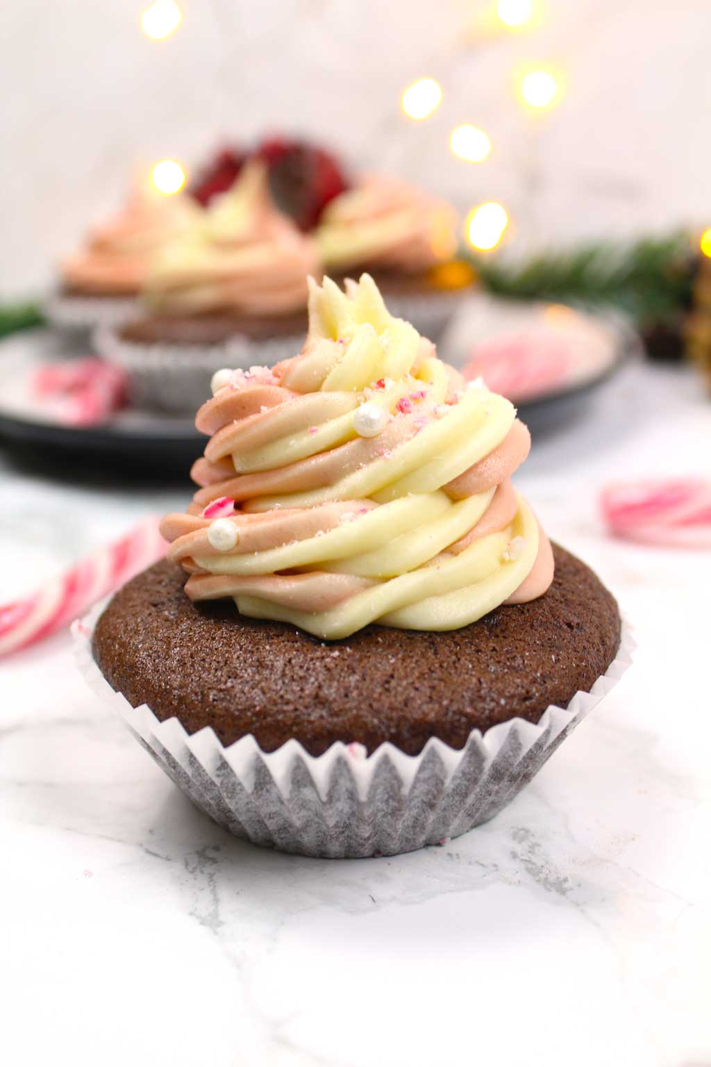 A candy cane cupcake with buttercream frosting on top.