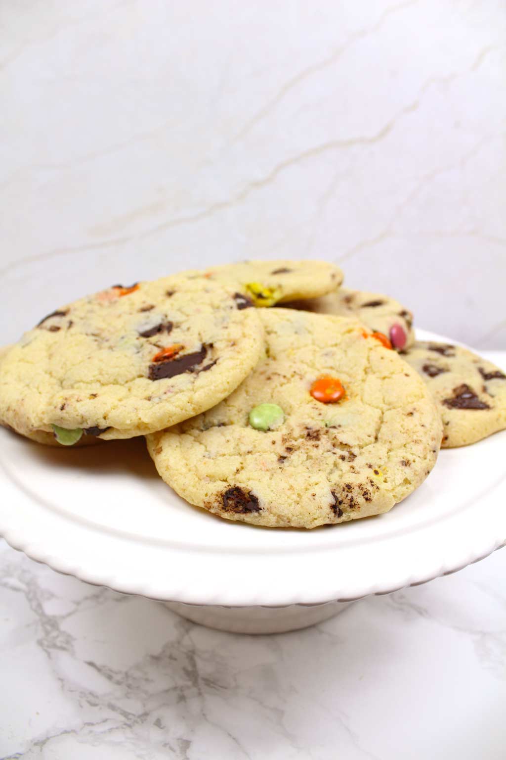 vegan rainbow chip cookies on a cake stand