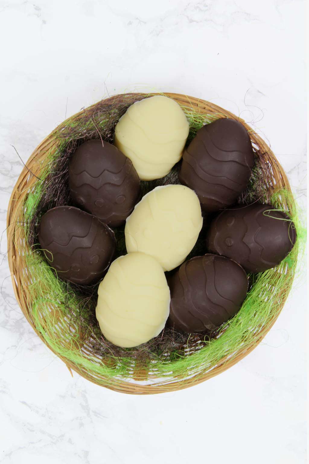 overhead shot of white and dark vegan creme eggs in a basket