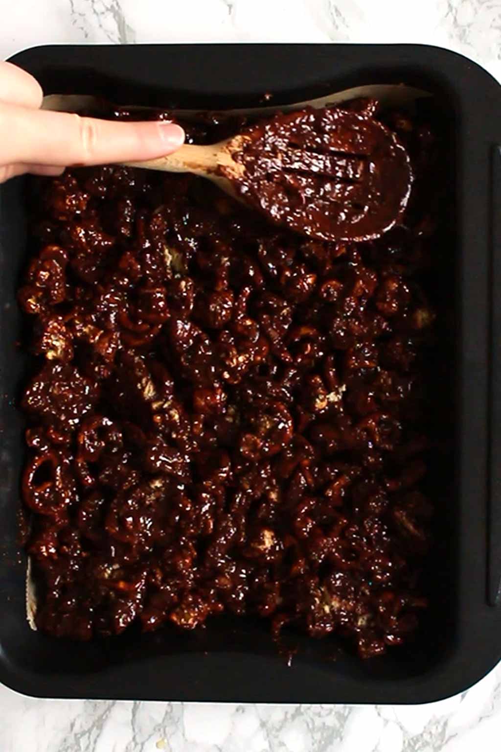 Pressing the rocky road Into Tin using a wooden spoon