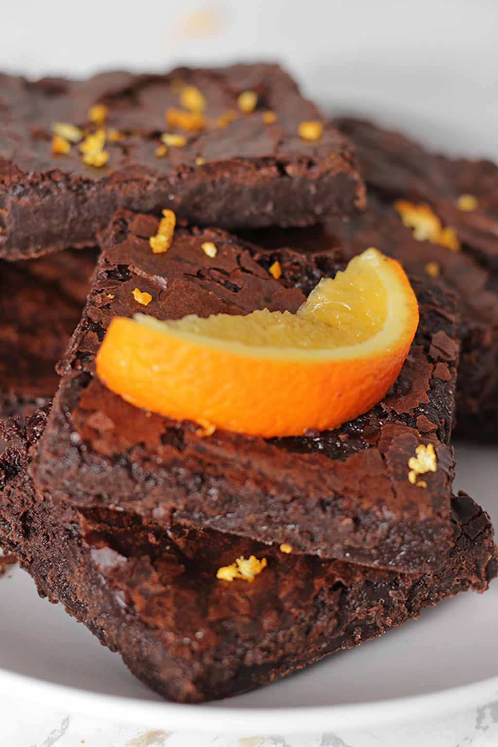 A Pile Of Chocolate Orange Brownies With An Orange Wedge On Top