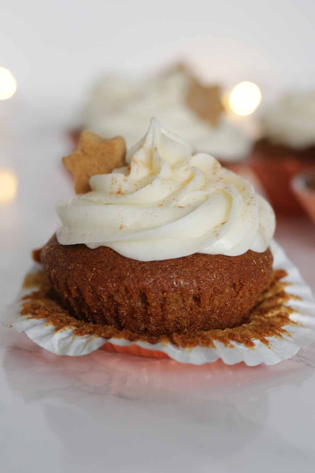 An Unwrapped Cupcake With Fairy Lights In The Background.