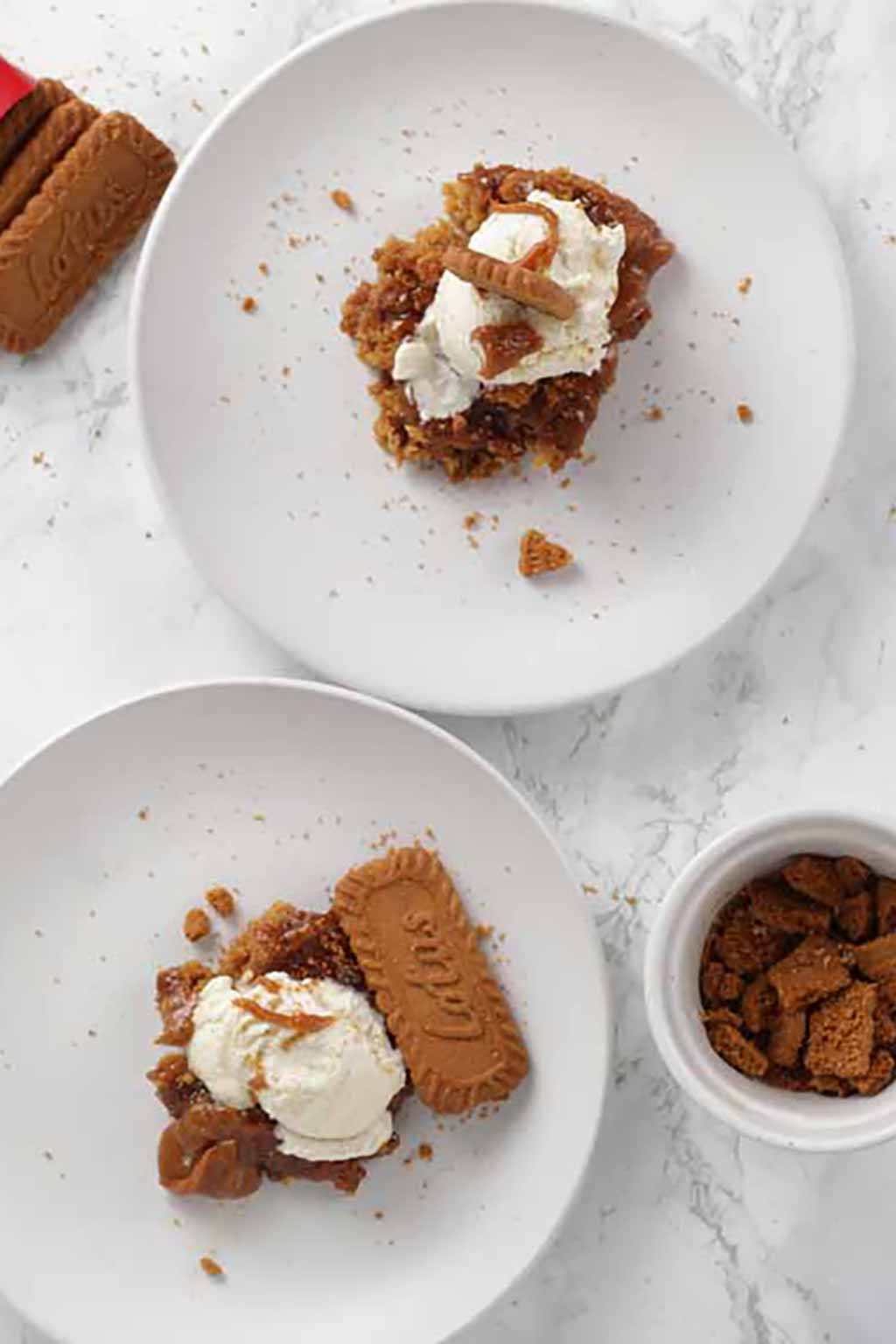 Two White Plates Each Containing 1 Slice Of Pudding With Ice Cream And Biscoff Cookies On Top