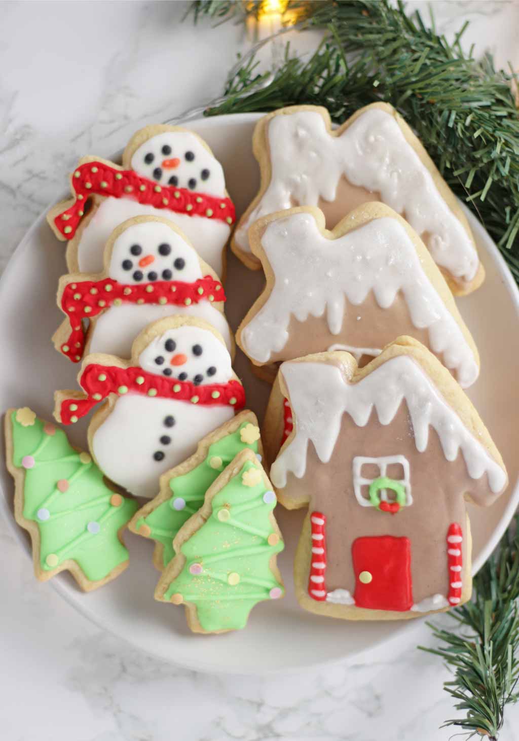 cookies decorated with royal icing on a plate. Christmas tree cookies, gingerbread house cookies and snowmen cookies.