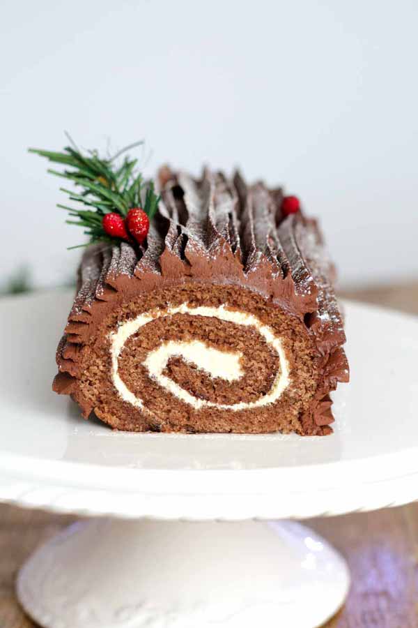 Vegan Chocolate Yule Log with red berries and a green sprig on top