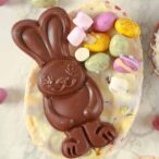 a chocolate bunny on top of a white cheesecake filled Easter egg